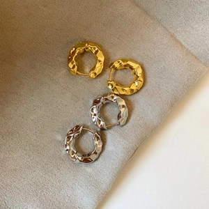 Detail of hammered texture metal earrings in gold and silver finish with irregular design