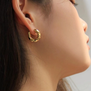 Detail of golden hoop earring with hammered texture worn by a model in macro view