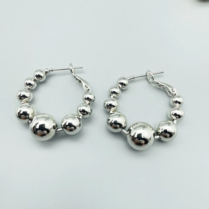 Close-up of polished silver beaded hoop earrings with a gradient sphere design