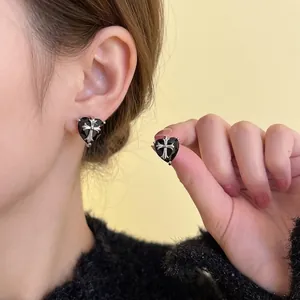 Elegance black heart stud earrings featuring a silver cross design worn by a model
