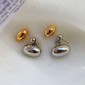 Detail of 18K gold and silver two-tone bean drop earrings with a polished mirror finish
