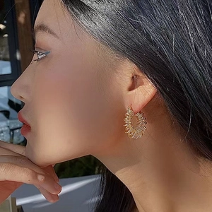 Modern gold coiled spring hoop earrings featuring a stylish spiral textured metal design