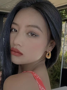 Detailed view of textured gold spiral hoop earrings worn by a model for trendy style