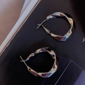 Detailed close-up of silver twisted metal hoop earrings with elegant geometric design