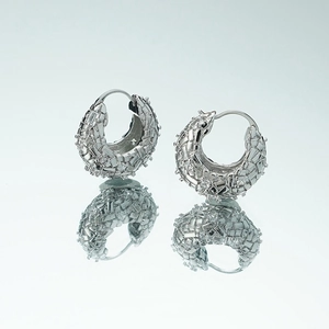 Detail of silver C-shape hoop earrings with geometric pave texture and mirror reflection
