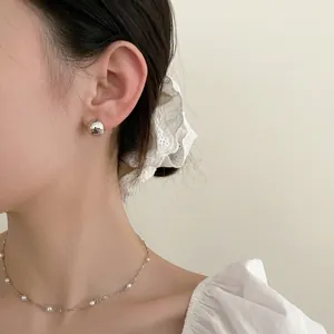 Boucles d'oreilles sphériques argentées et collier de perles fin sur mannequin femme