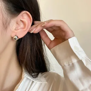 Gros plan d'une boucle d'oreille boule argentée minimaliste portée pour un look chic