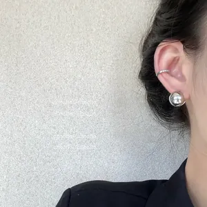 Gros plan sur un clou sphérique argenté et une manchette d'oreille ronde minimaliste