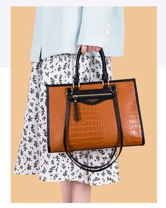 Modèle portant un grand sac cabas marron à motif crocodile et poignées contrastées