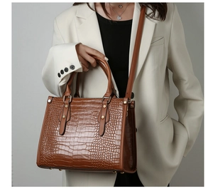 Detail of crocodile embossed leather texture on brown tote with gold metal studs