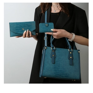 Macro detail of teal crocodile embossed faux leather three-piece bag set with gold studs