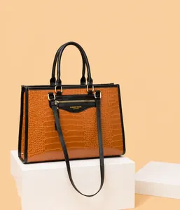 Détail du sac à main marron à motif crocodile avec fermeture éclair dorée et poignées