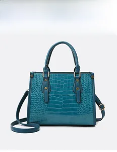 Detail of dark blue crocodile pattern handbag showing gold hardware and texture