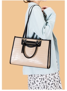 Détail d'un grand sac cabas blanc cassé à motif crocodile avec bordure noire et zip doré
