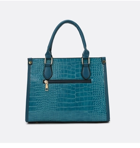 Close-up of turquoise crocodile embossed leather texture and gold hardware on tote bag