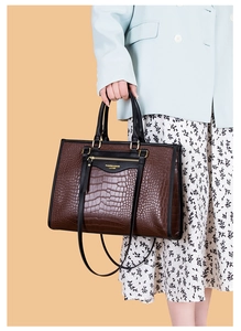 Détail d'un sac cabas marron foncé avec texture crocodile et accents métalliques dorés
