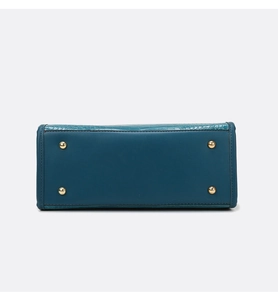 Macro view of blue crocodile pattern handbag base with four gold protective metal feet