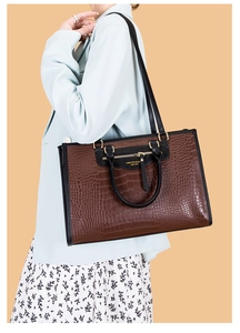 Détail d'un cabas marron foncé avec motif crocodile et détails dorés sur mannequin