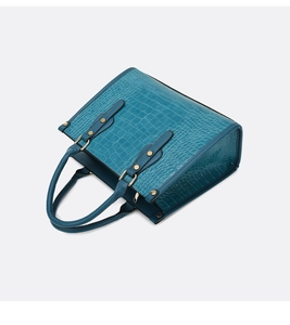 Detail view of crocodile embossed leather tote bag with sturdy gold hardware rivets
