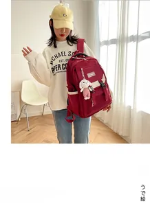 Detail view of burgundy waterproof school backpack with cute pink rabbit keychain