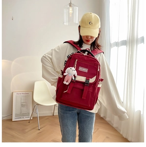 Detail view of red school backpack with flap buckles and cute white rabbit keychain