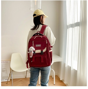 Macro detail of dark red nylon school bag with zippers and cute rabbit plush pendant