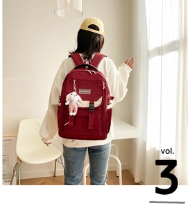 Detail of red nylon backpack featuring a flap closure and cute white rabbit plush charm