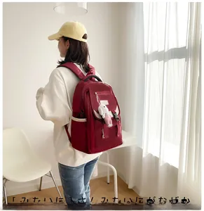 Red waterproof nylon backpack with plush bunny charm shown from a back perspective
