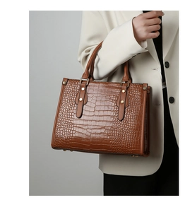 Macro shot of brown crocodile embossed leather texture with gold metal buckle details