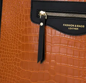 Détail du sac en cuir orange embossé crocodile avec fermeture éclair dorée et logo