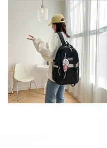 Side view of black casual nylon backpack with multiple pockets and white rabbit pendant