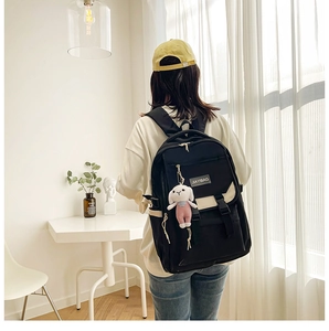 Detailed view of bicolor nylon backpack with plush rabbit pendant on a female model