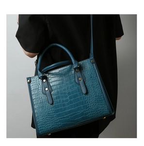 Detail of dark blue crocodile pattern handbag with gold studs and adjustable strap
