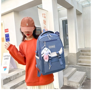 Close-up of blue student backpack with white buckle detail and cute rabbit keychain