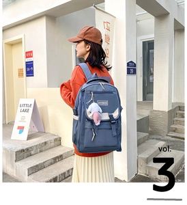 Detail view of navy nylon backpack with JIAYIBAG logo and plush pendant accessory