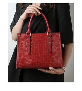 Close-up of elegant dark red handbag featuring crocodile texture and gold hardware