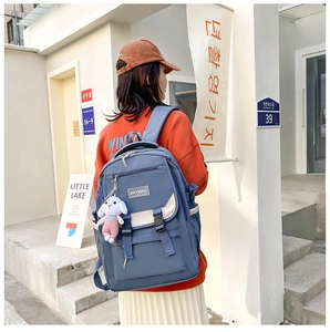 Close-up of navy backpack flap with white contrast panels and rabbit plush keychain