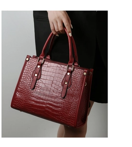 Close-up of wine red crocodile embossed leather tote bag with gold stud hardware details