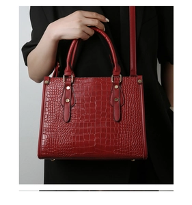 Close-up of dark red embossed crocodile pattern tote bag with vintage gold rivets