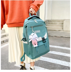 Detail of mint green school backpack with white pockets and cute rabbit doll keychain