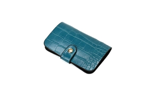 Detail of teal crocodile pattern folding wallet with a gold snap button closure
