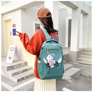 Detail of green nylon backpack with cute bunny pendant shown on model's back
