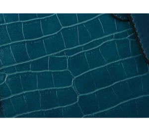 Close-up of teal faux leather bag showing embossed crocodile pattern and stitching