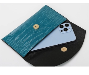 Detailed interior of peacock blue crocodile embossed clutch with phone for scale