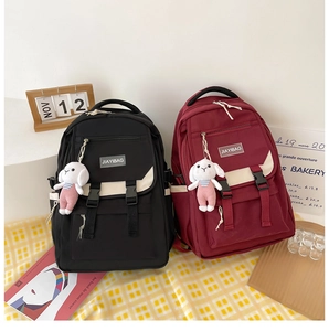 Detailed view of canvas backpacks in black and wine red with cute bunny pendants