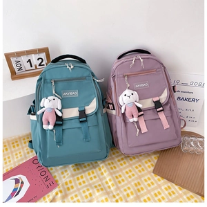Detail of blue and purple nylon backpacks with buckle flaps and cute rabbit plush charms