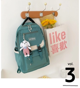 Detail view of mint green backpack with white plush rabbit charm and buckle pocket