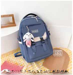 Detailed shot of a blue nylon backpack with cream straps and a cute rabbit pendant
