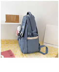 Blue nylon backpack detail showing side pocket, adjustable buckle and plush bunny charm