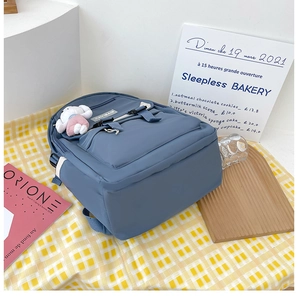Blue minimalist backpack detail featuring a cute white rabbit plush toy and side pocket